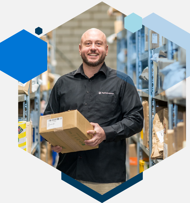 Simon Kühn im Paketlager mit einem Paket in der Hand